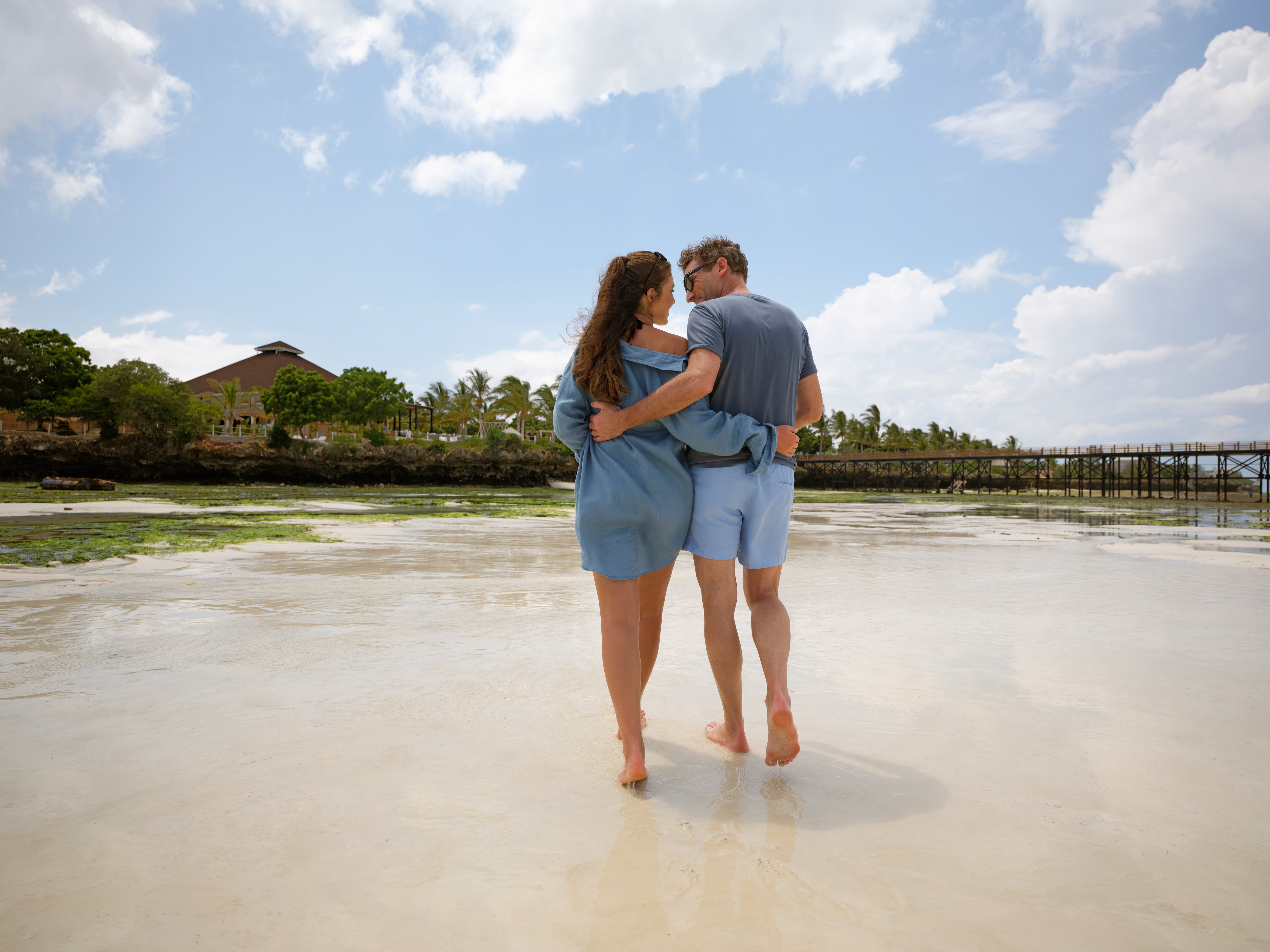 Ein Paar spaziert barfuss am Strand und genießt den Urlaub im Aldiana Resort.