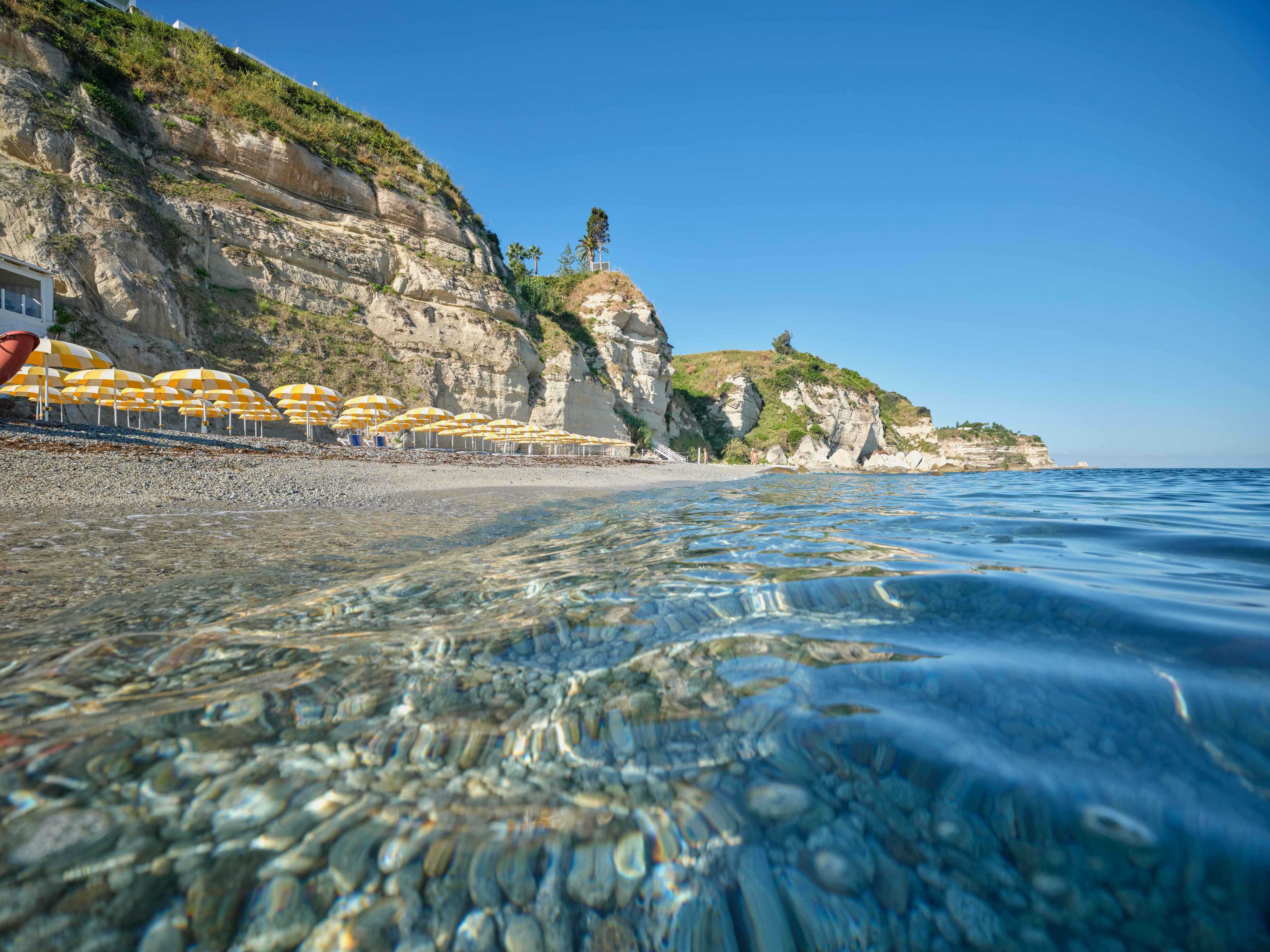 Ein Blick auf den ruhigen Strand mit Klippen und loungenden Gästen bei Aldiana Premium Cluburlaub