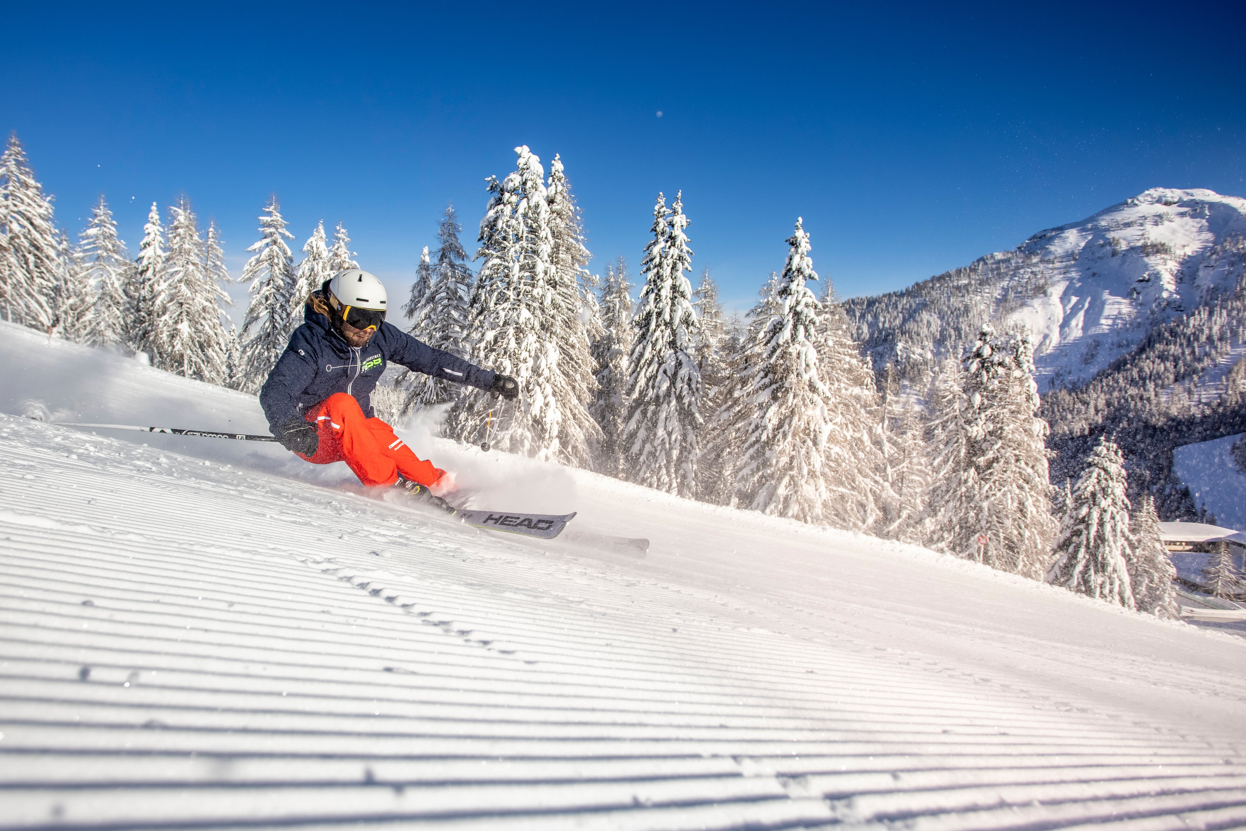 Skiender auf schneebedeckter Piste in Winterlandschaft bei Sonnenlicht
