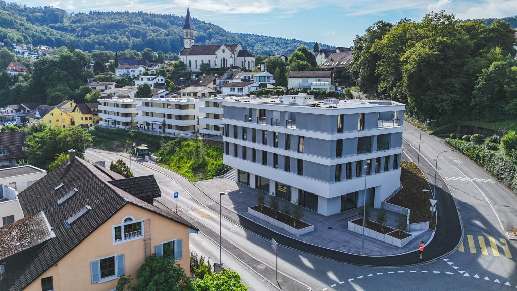Moderne weiße Gebäudestruktur an einer Straße mit umliegenden Wohnhäusern und grüner Umgebung aus dem Artikel