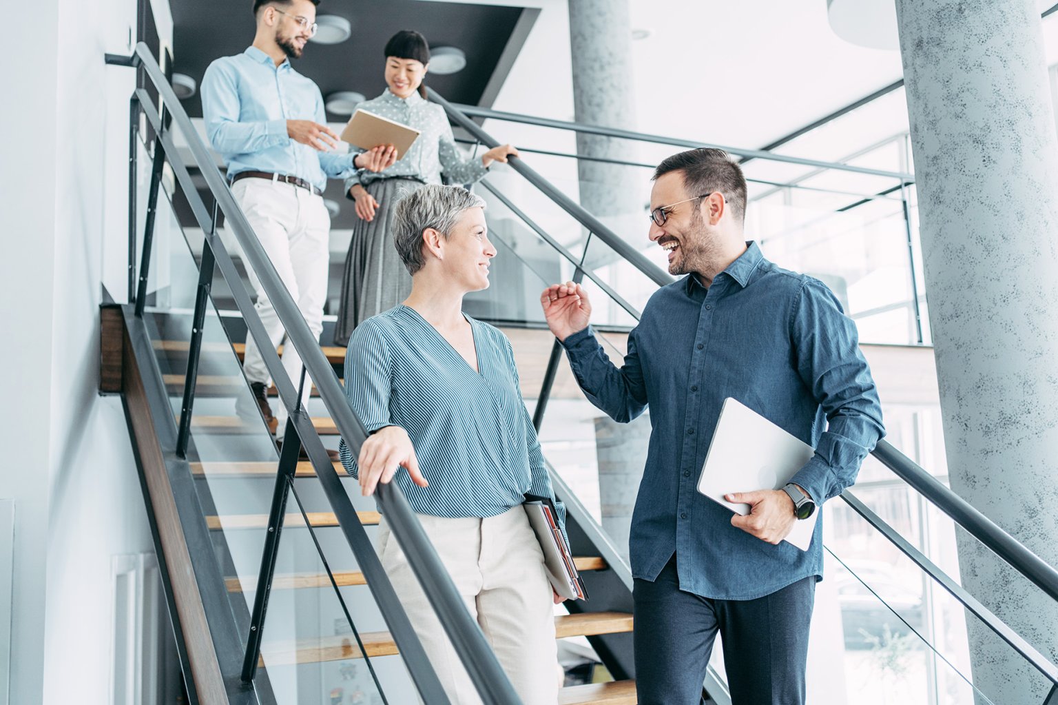 Aufnahme einer Gruppe von Kollegen, die sich unterhalten, während sie in einem modernen Büro die Treppe hinuntergehen. Geschäftsleute in Bewegung auf der Treppe im Büro.
