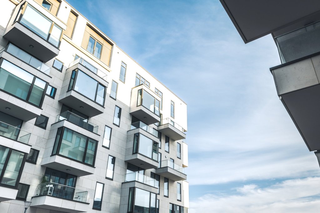 Moderne Wohnfassade mit Balkonen und grossen Fenstern gegen den blauen Himmel.