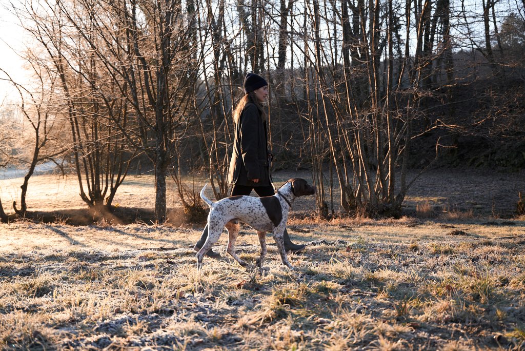 Frau mit Hund spazieren in der Winterzeit im Wald.