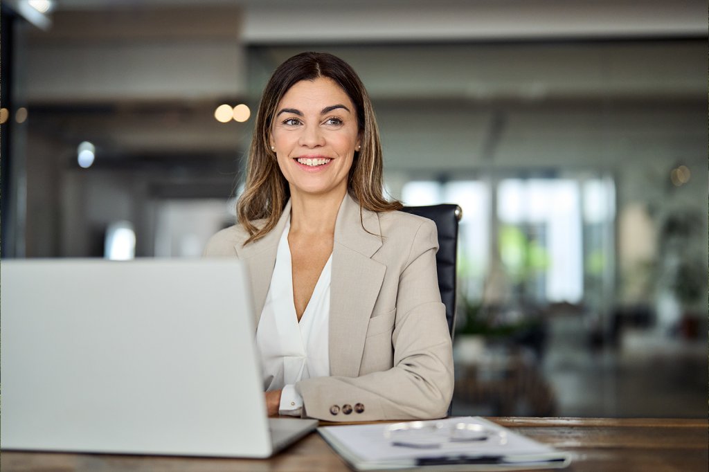 Eine freundliche Frau am Schreibtisch mit Laptop, bereit für neue Ideen.