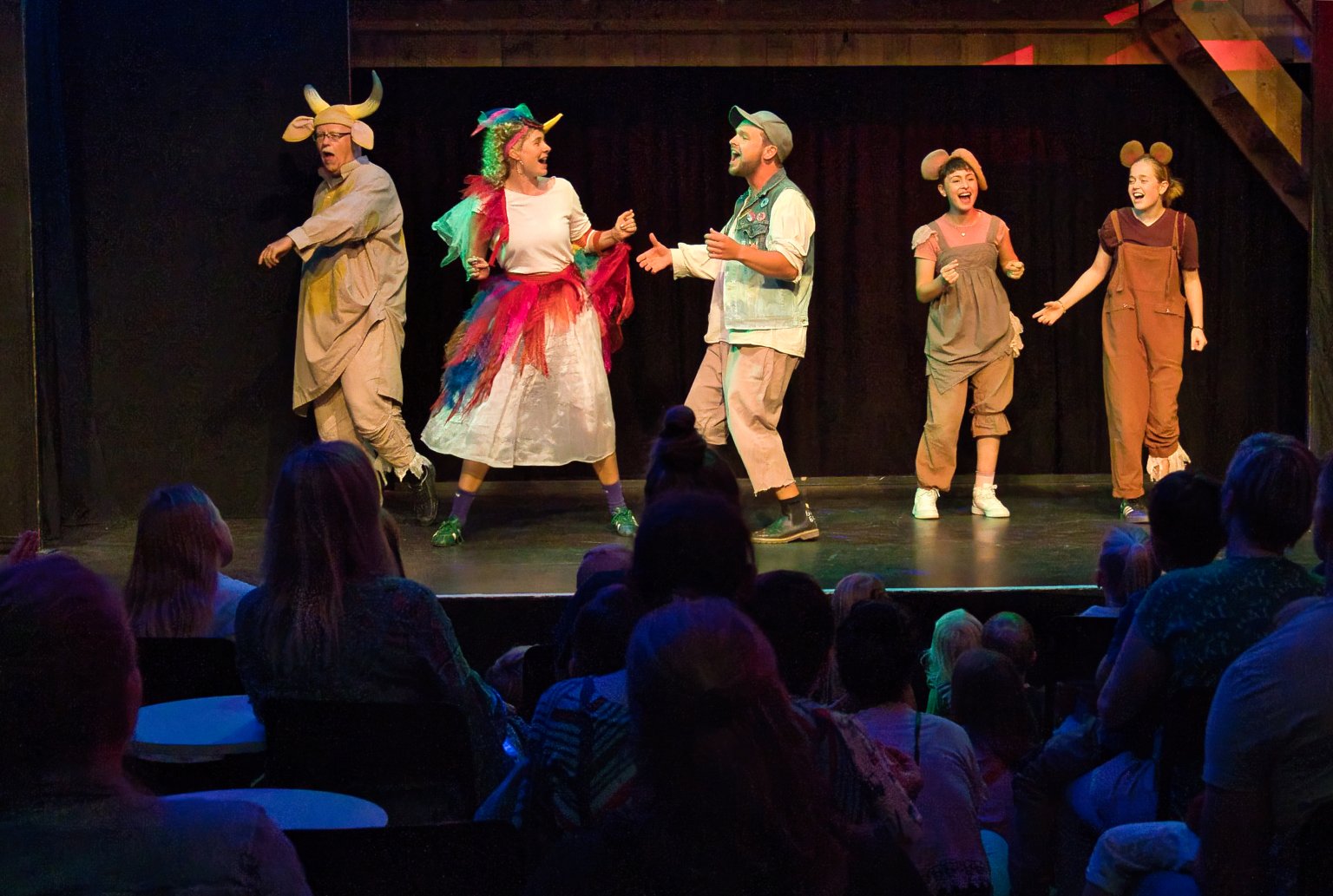 Menschen im Tierkostüm auf Bühne während einer Theateraufführung vor Publikum