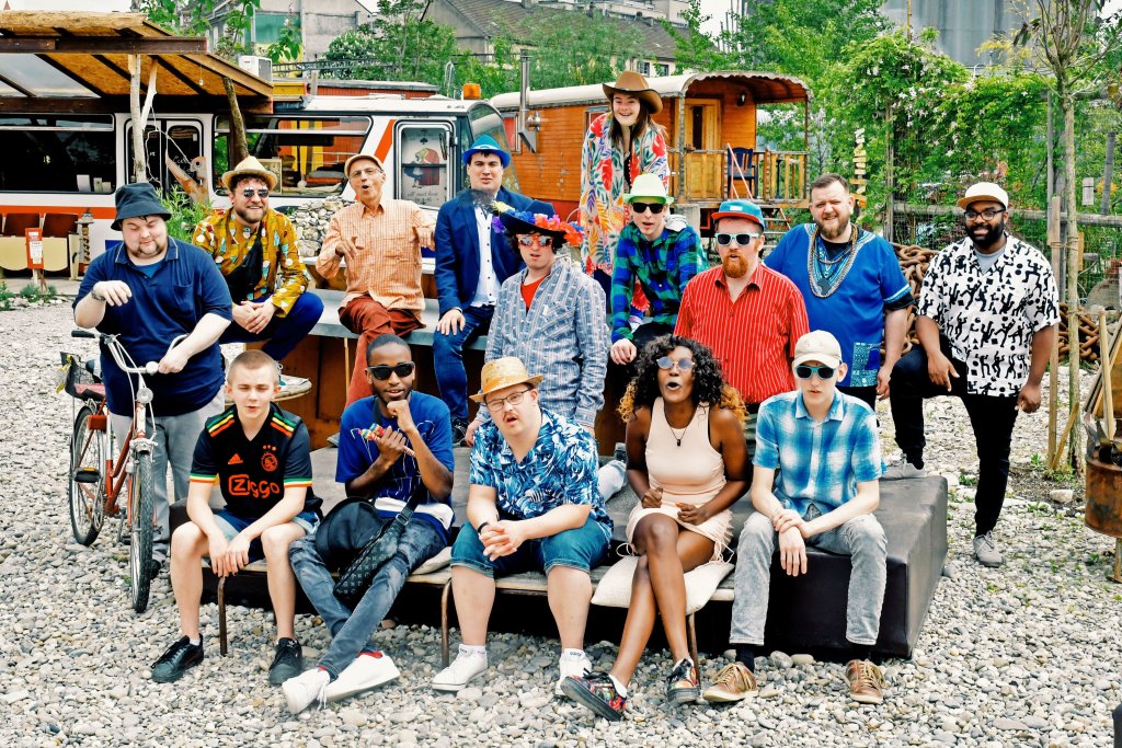 Gruppenfoto mit 14 Personen vor einem Bahnwagen in einem sonnigen Außenbereich von Boxidos.