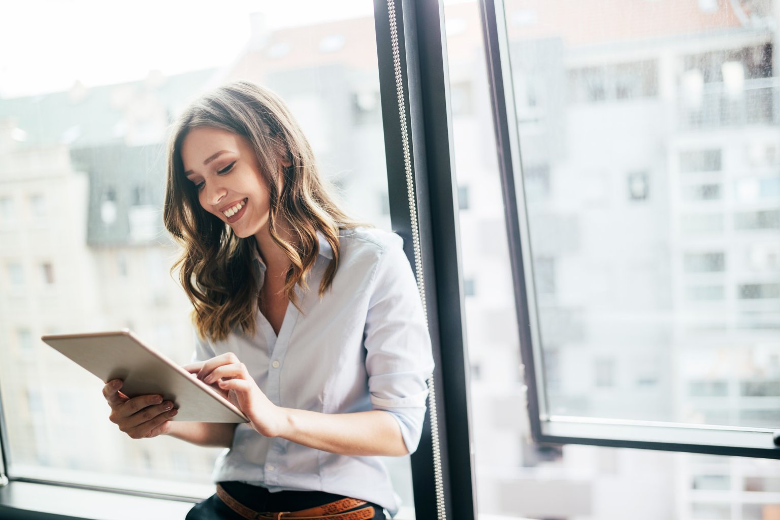 Eine Frau mit Tablet freut sich über digitale Dienstleistungen der BLKB.