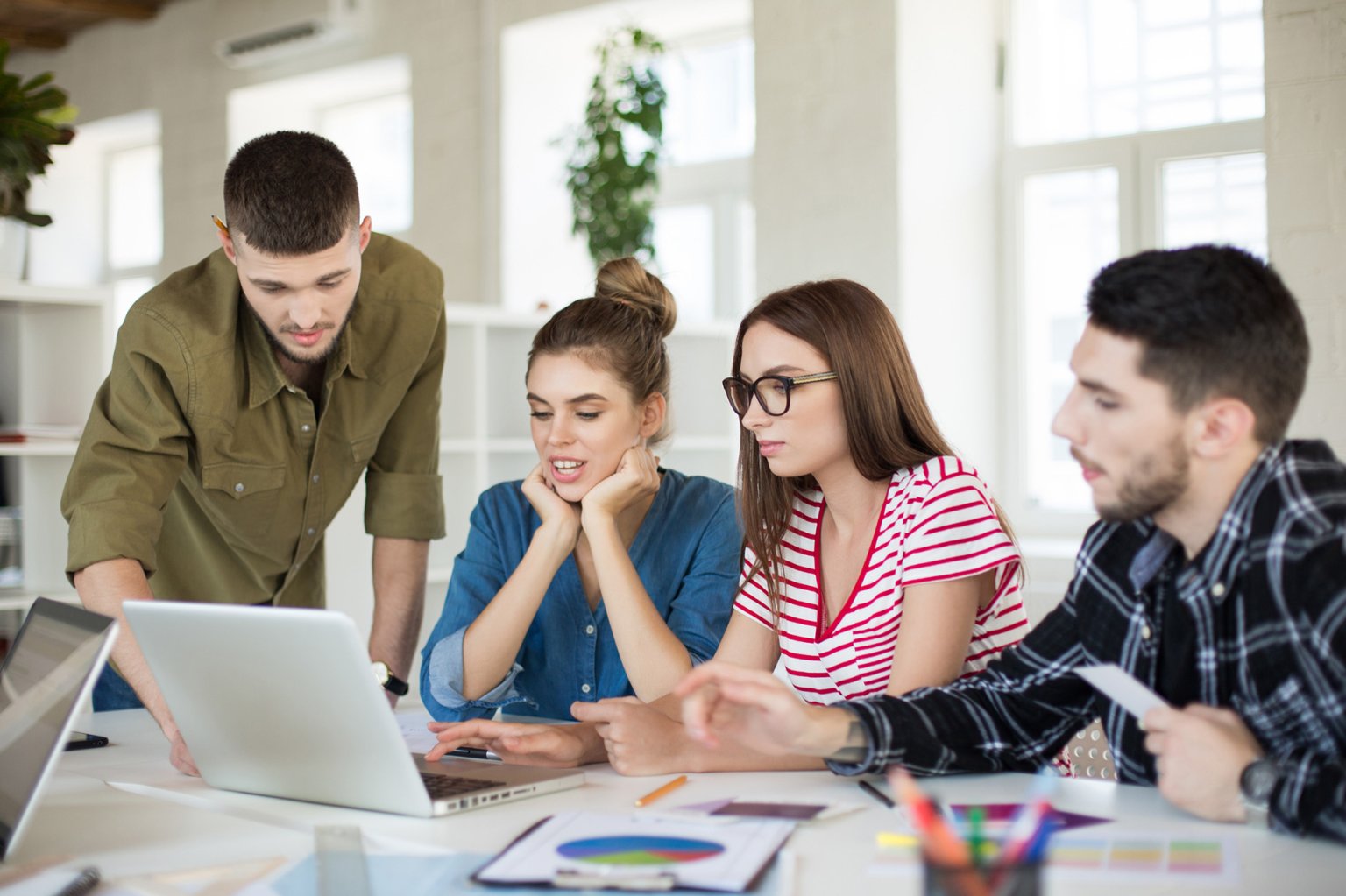 Ein Team arbeitet gemeinsam an einem Laptop in einem modernen Büro.