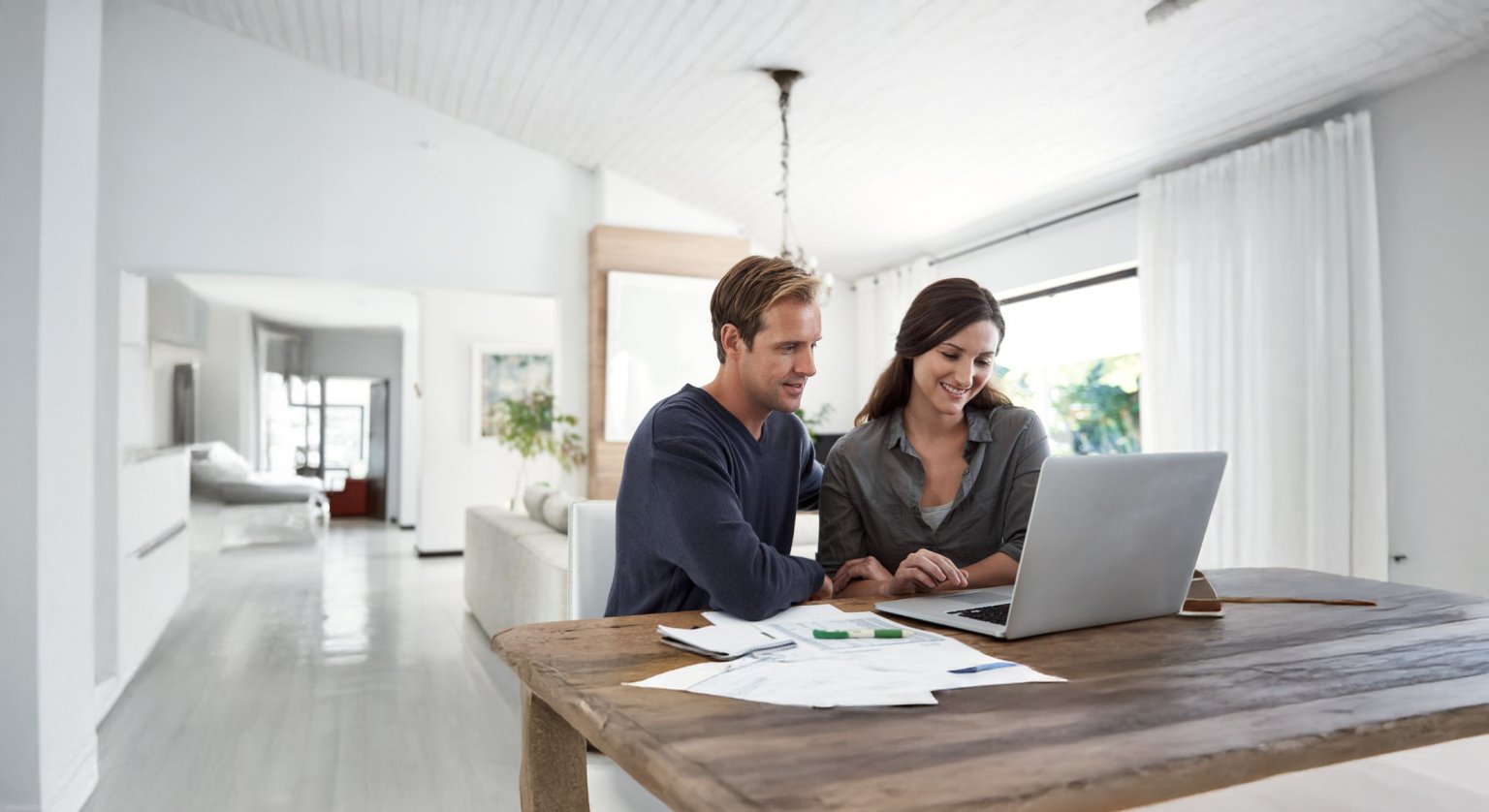 Eine Frau und ein Mann arbeiten an einem Laptop in einem hellen Raum.