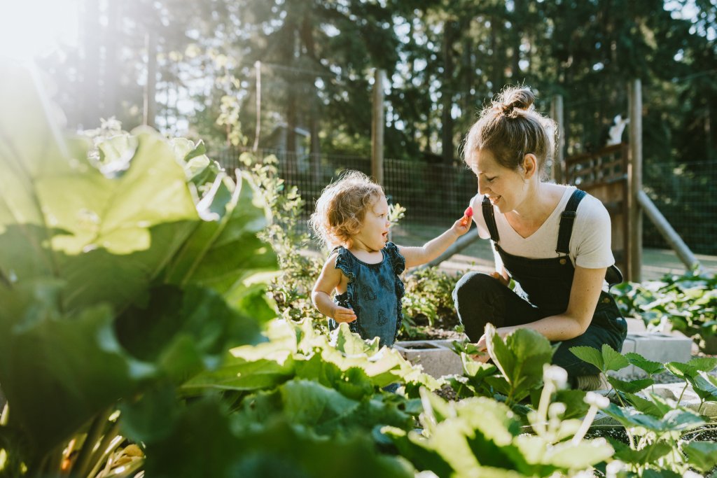 Mutter und Kind im Garten, Freude beim Ernten von frischem Gemüse.