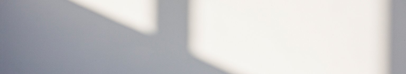 Eine schlichte weisse Wand mit einem Fensterschatten.