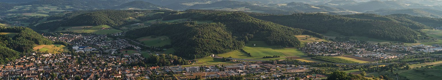 Landschaftsaufnahme mit Hügeln und einer Stadt im Vordergrund, typisch für die Region.
