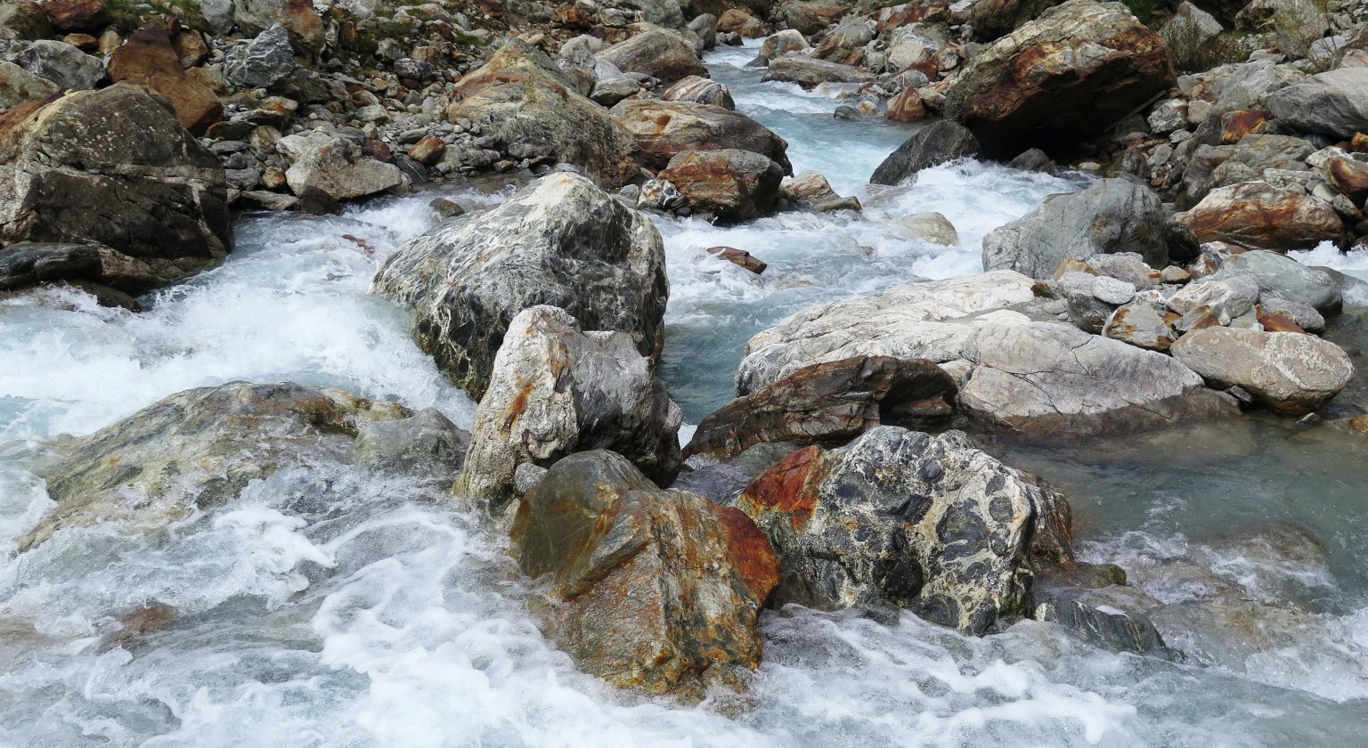 Ein Fluss mit klar fliessendem Wasser und glatten Steinen in einer natürlichen Umgebung. aus dem Artikel Private Credit unter Druck: Stresstest oder strukturelle Krise?