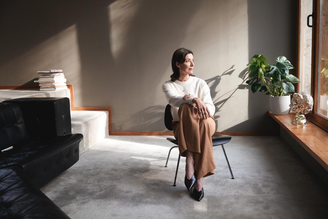 Frau sitzt auf einem Stuhl und sieht durch das Fenster. aus dem Artikel Stockwerkeigentum einfach erklärt