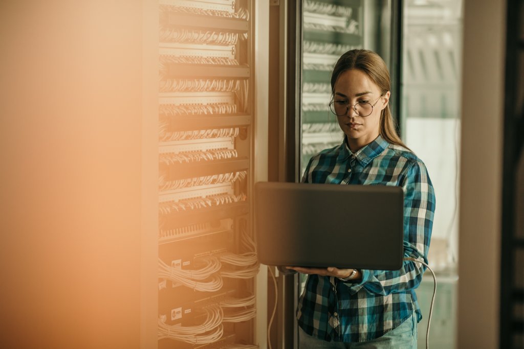 Eine Frau arbeitet mit einem Laptop in einem modernen Rechenzentrum.