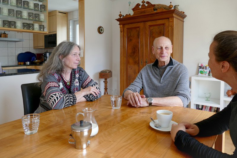 Ein freundliches Gespräch am Tisch, zwei Personen und eine Zuhörerin in heimischer Umgebung. aus dem Artikel Aus ökonomischer Sicht spricht alles für eine Sanierung