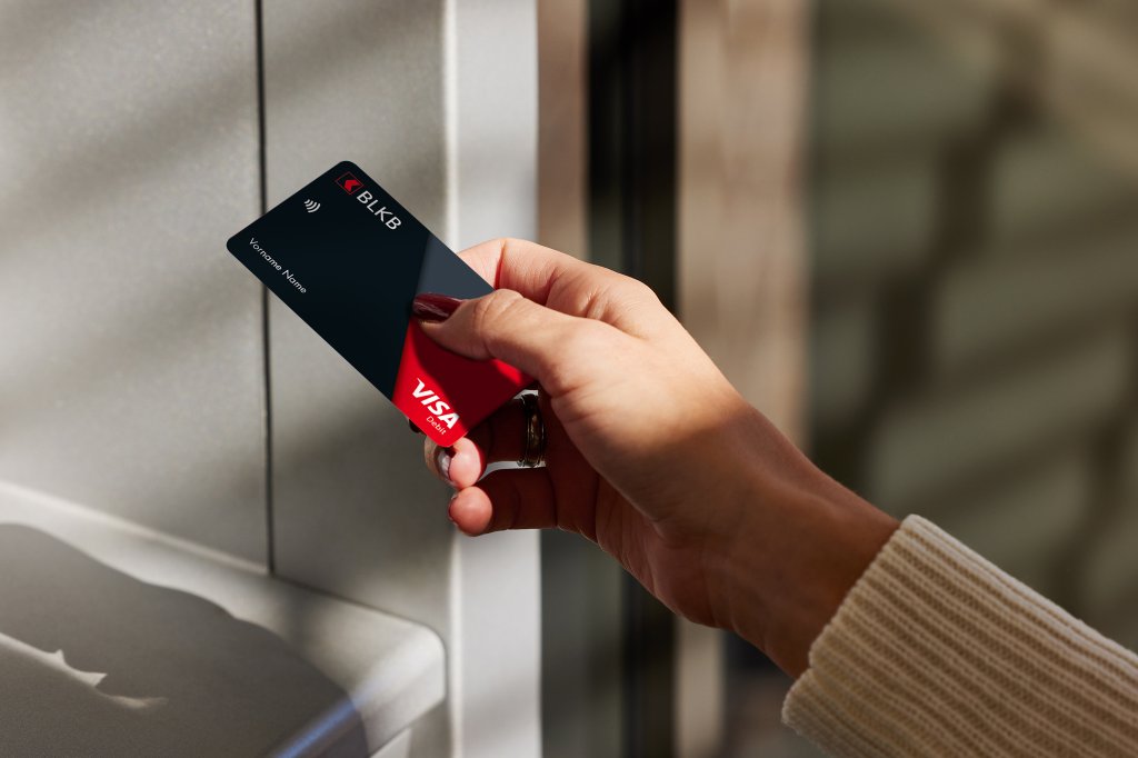 Eine junge Frau möchte mit ihrer BLKB-Karte Geld an einem Automaten abheben.