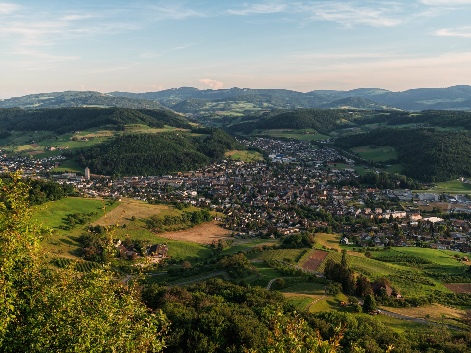 Ein malerischer Blick auf das Dorf mit sanften Hügeln und grünen Feldern.