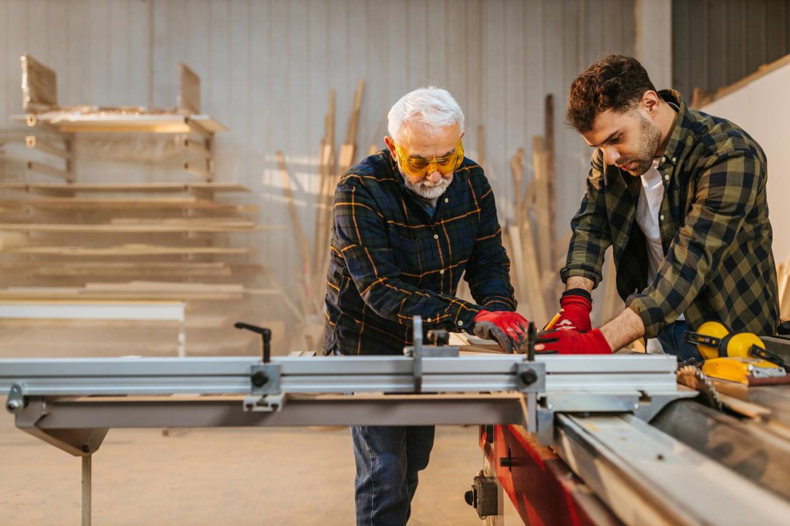 Zwei Männer arbeiten gemeinsam in einer Werkstatt an einem Holzbearbeitungsprojekt.