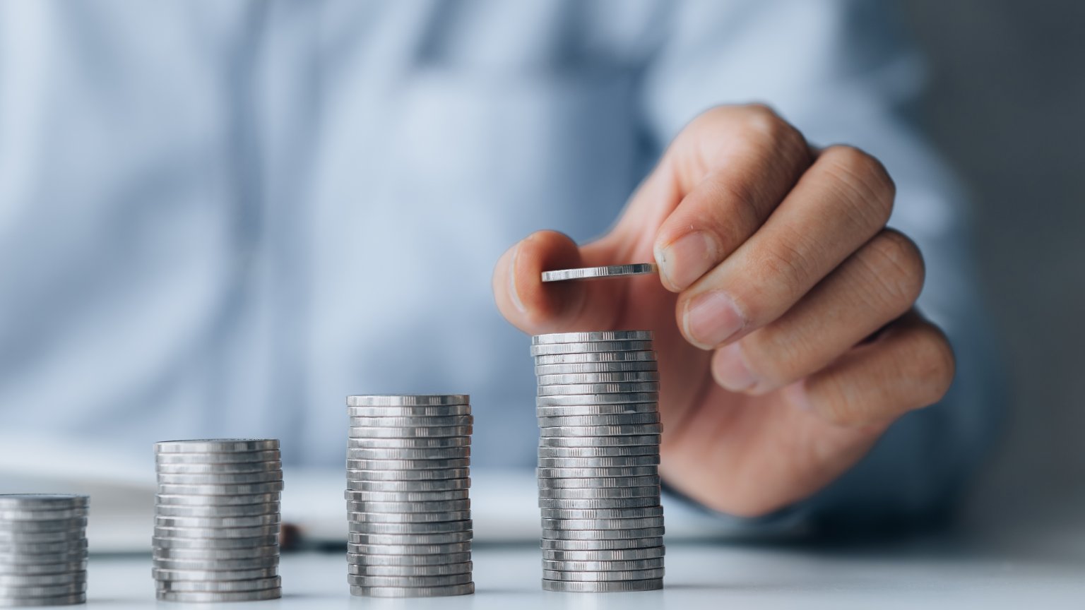 Eine Person zählt Münzen in 4 Stapeln. aus dem Artikel Was spricht für eine gestaffelte Investition?