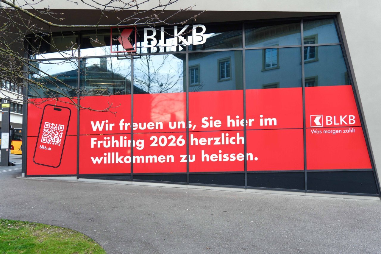 Fensterfront mit roten Werbebanner der BLKB-Niederlassung in Liestal und QR-Code zu blkb.ch.
