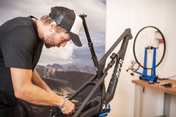 Ein Junger Mann von ARC8 Bicycles mit Kappe repariert ein Fahrrad.