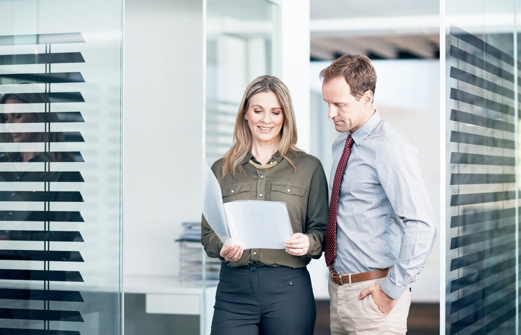 Zwei Mitarbeiter der BLKB besprechen Unterlagen in modernem Büro.