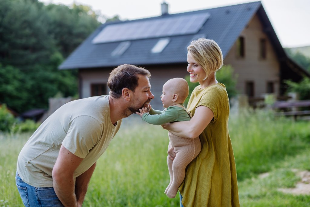 Familie in natürlicher Umgebung vor einem modernen Haus mit grünem Garten.