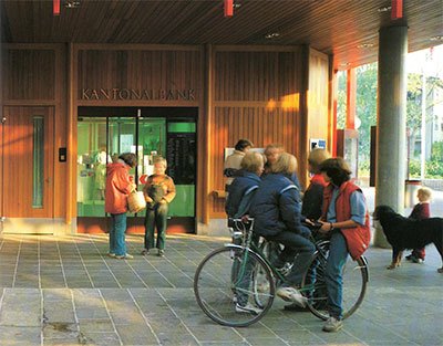 Menschen vor der BLKB-Bankgebäude im Freien mit Fahrrädern im Jahr 1983