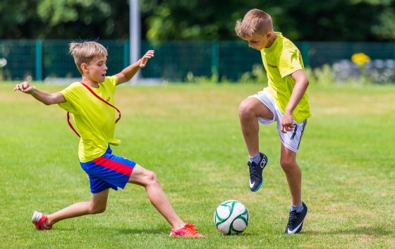 2 Jungs spielen draussen Fussball beim Kinder-Camps.