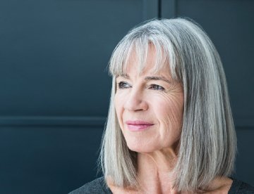 Frau mit grauen Haaren lächelt nachdenklich in die Kamera. aus dem Artikel Guthaben aus der Säule 3a: investieren oder ruhen lassen?