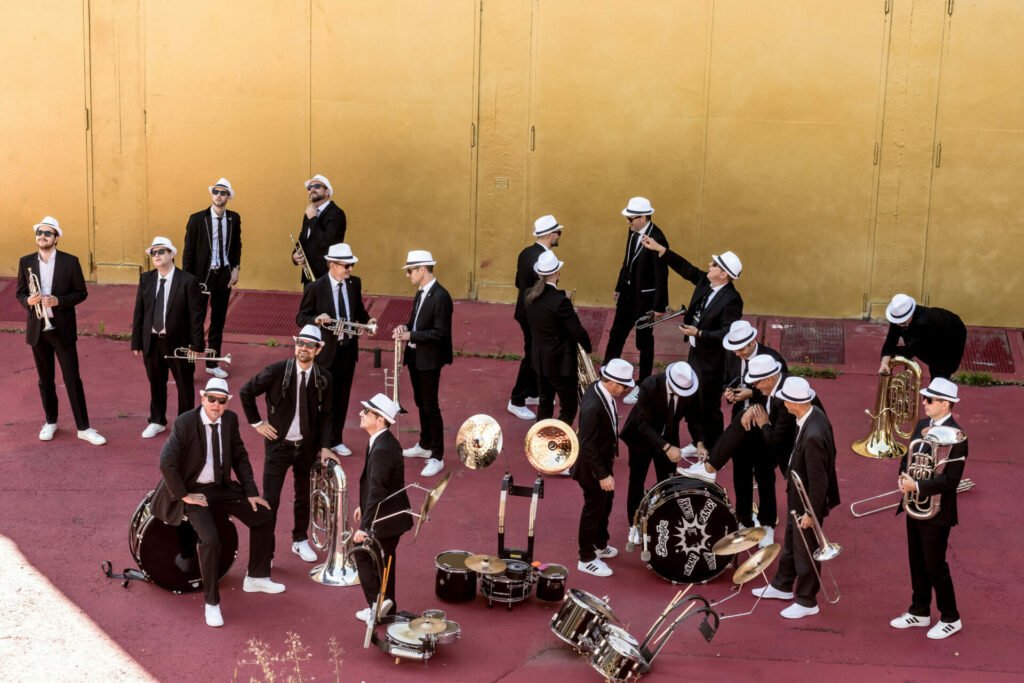 Gruppe von Musikanten namens 'Bieranjas' in schwarzen Anzügen mit weissen Hüten, präsentiert ihre Blasmusik.