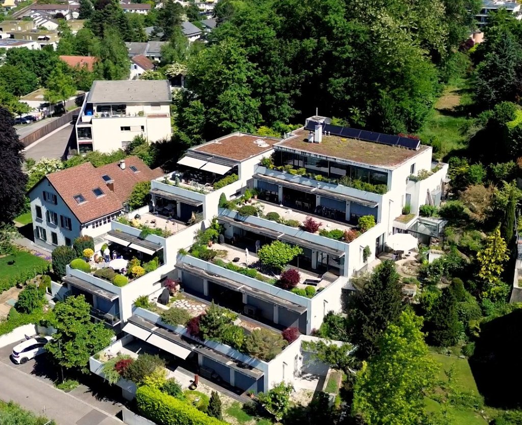 Mehrstöckiges Wohngebäude mit terrassierten Gärten und viel Grün.