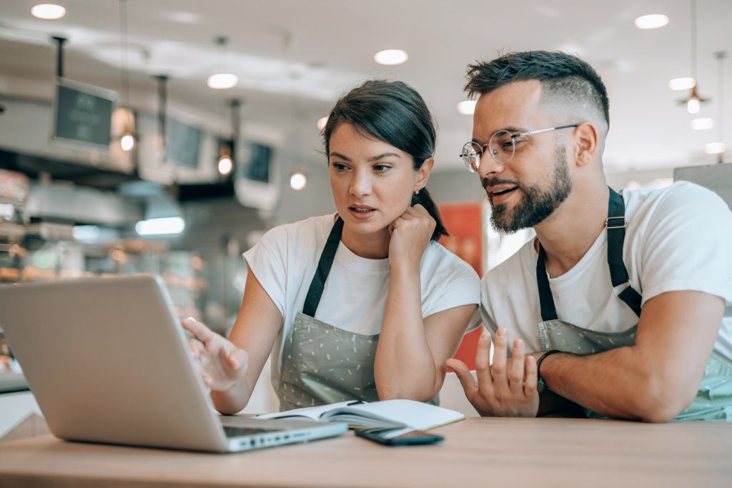 Zwei Fachleute führen eine Diskussion, während sie Inhalte auf einem Laptop überprüfen.