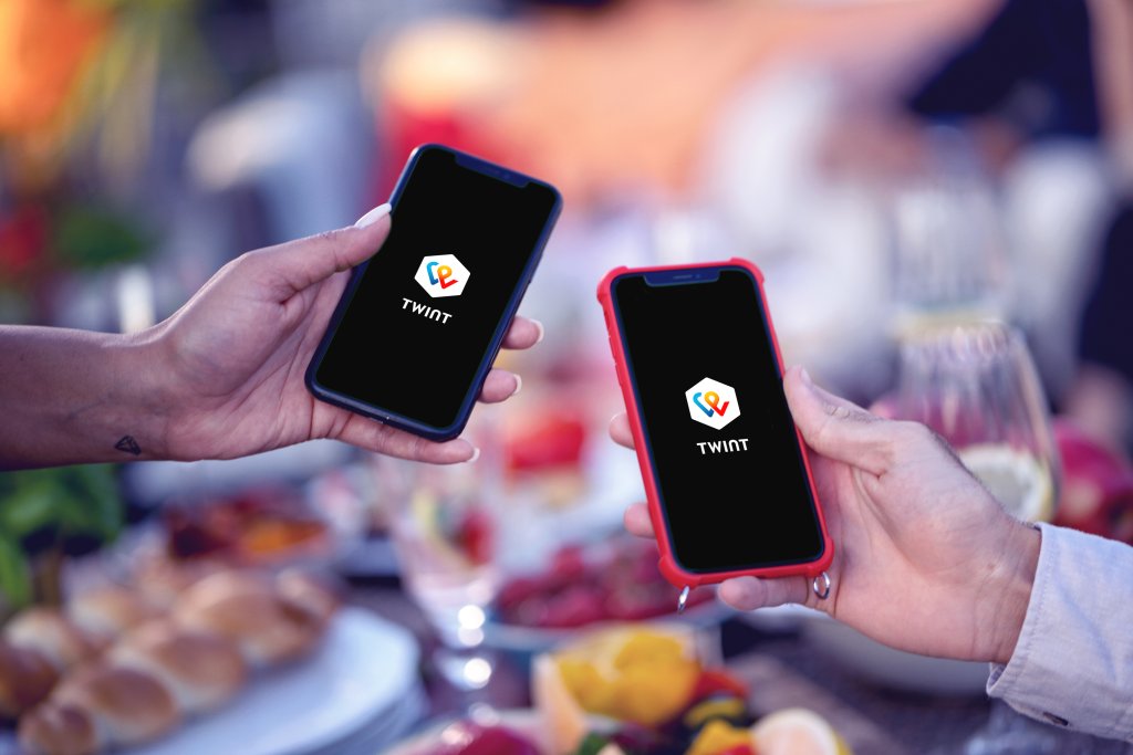 Zwei Hände halten Smartphones mit TWINT Logo beim festlichen Anlass.