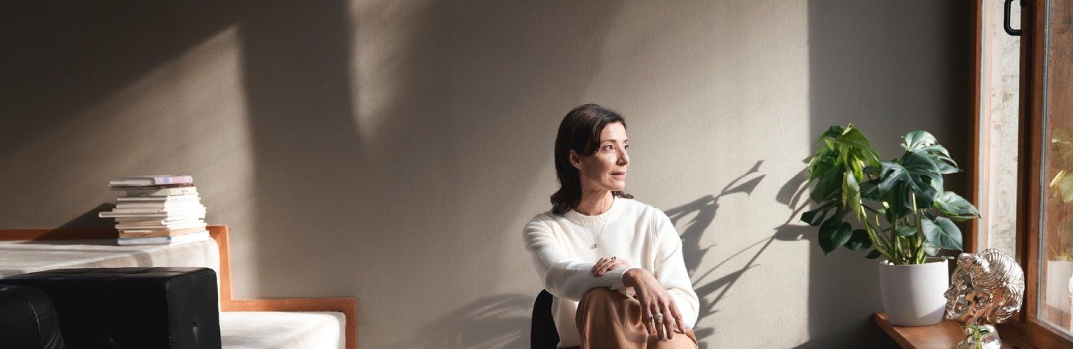 Frau sitzt auf einem Stuhl und sieht durch das Fenster.