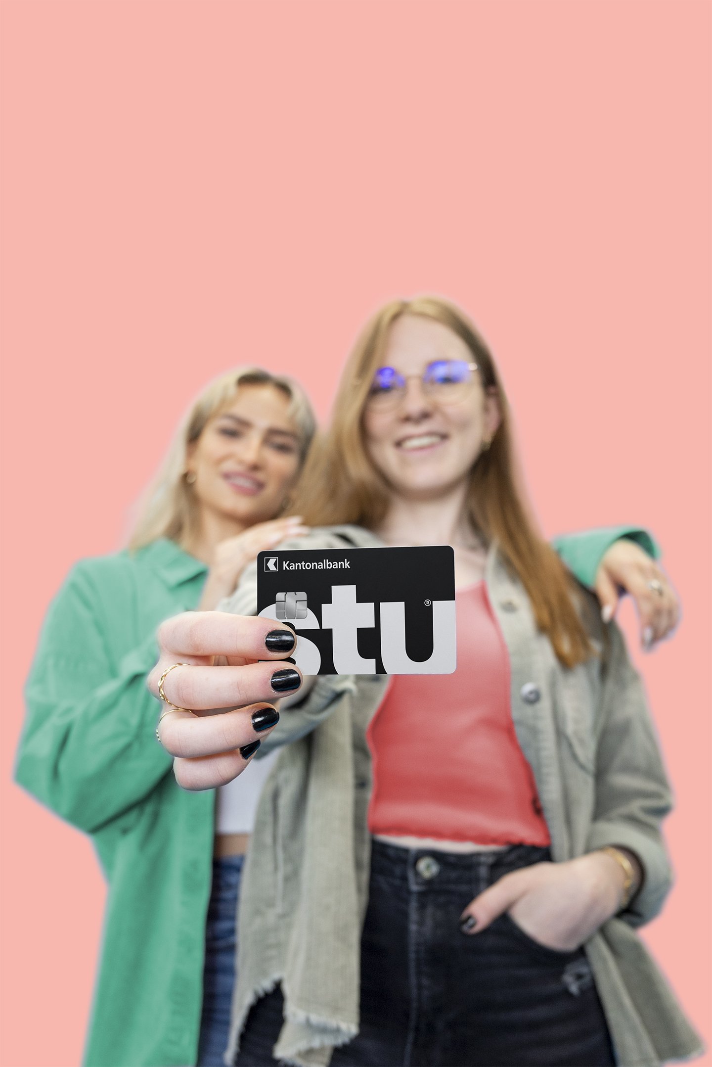 Zwei Frauen zeigen eine Karte der Basellandschaftlichen Kantonalbank vor einem bunten Hintergrund.