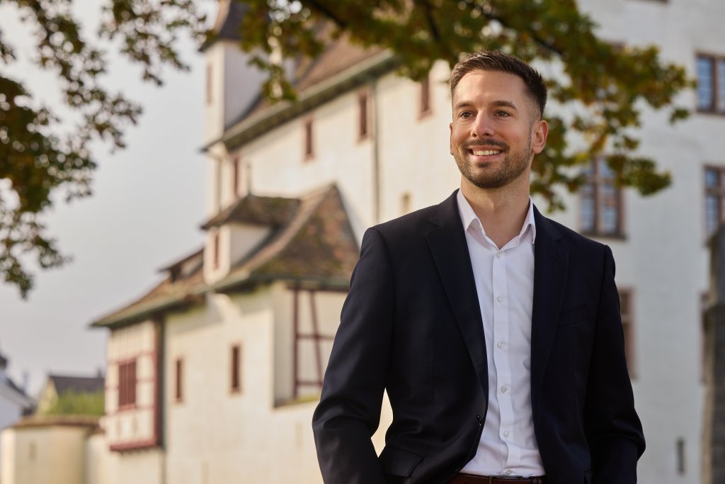Pascal Inderwildi im Anzug vor einem historischen Turmgebäude in der Nordwestschweiz.