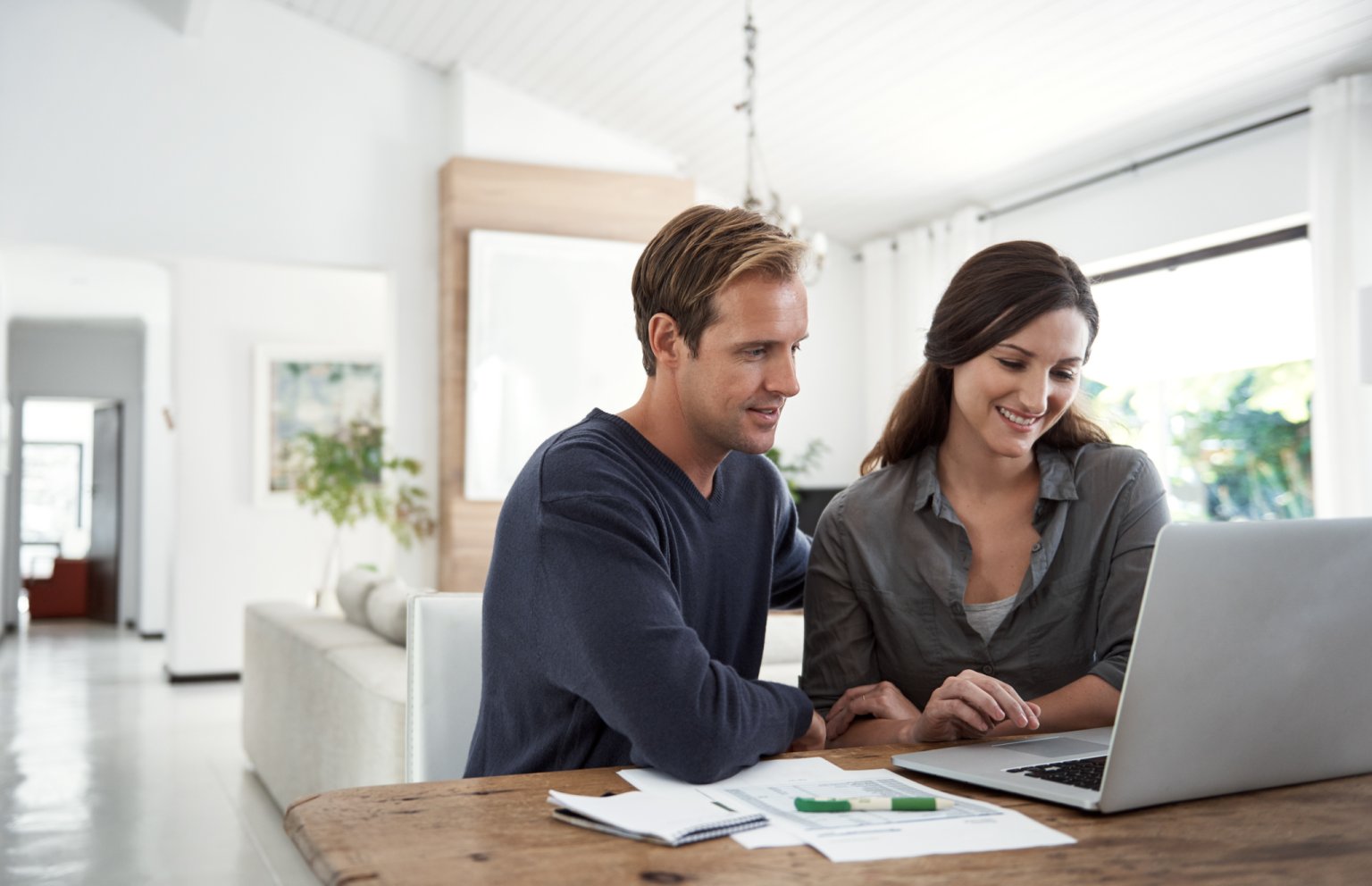 Ein Paar, das zusammen an einem Laptop in einem modernen Zuhause arbeitet.