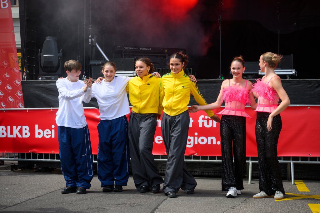 Sechs junge Frauen stehen nebeneinander, zwei tragen gelbe Jacken, vier tragen bunte Kleidung.