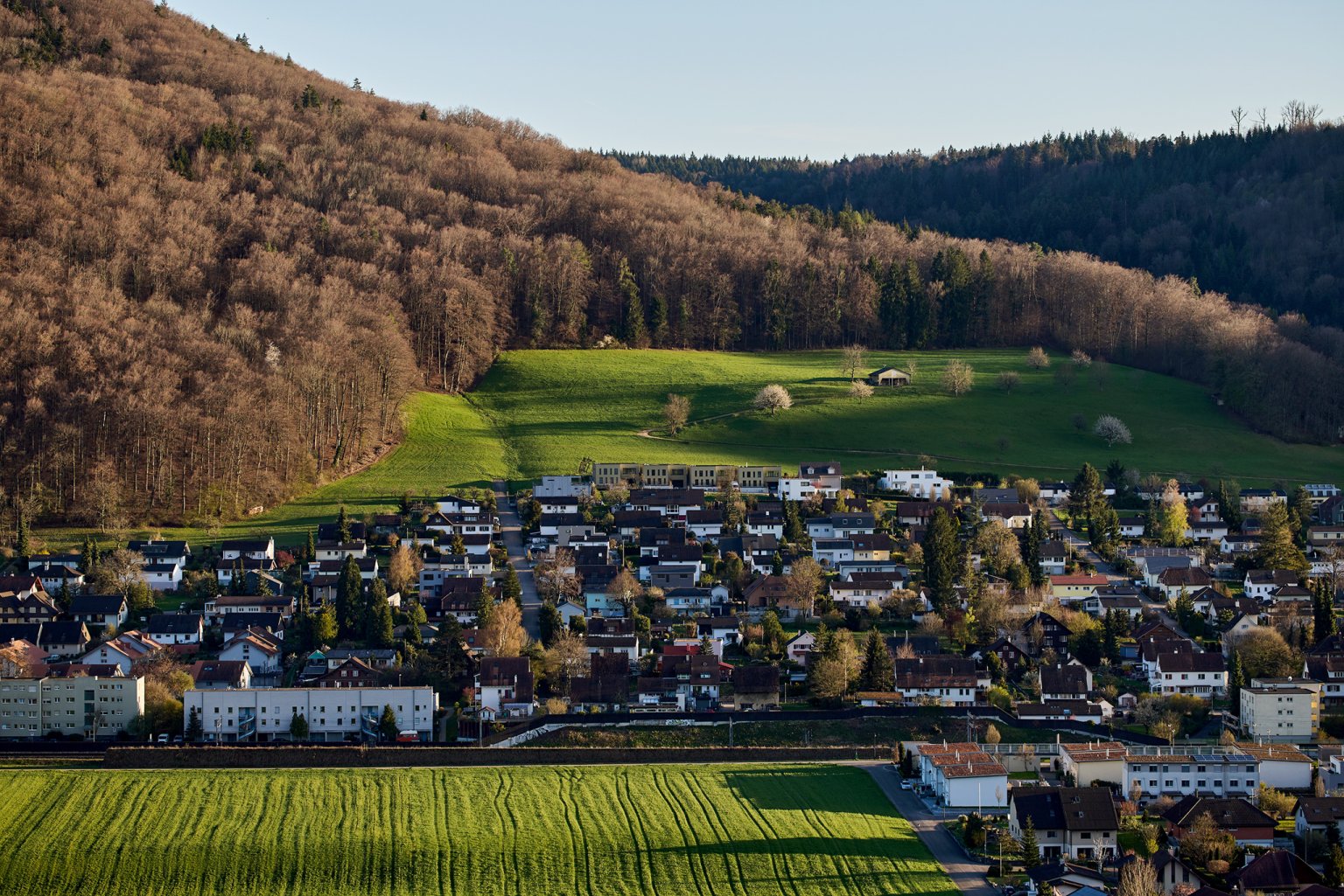 Ein malerischer Blick auf ein Dorf, umgeben von grünen Wiesen und Hügeln.