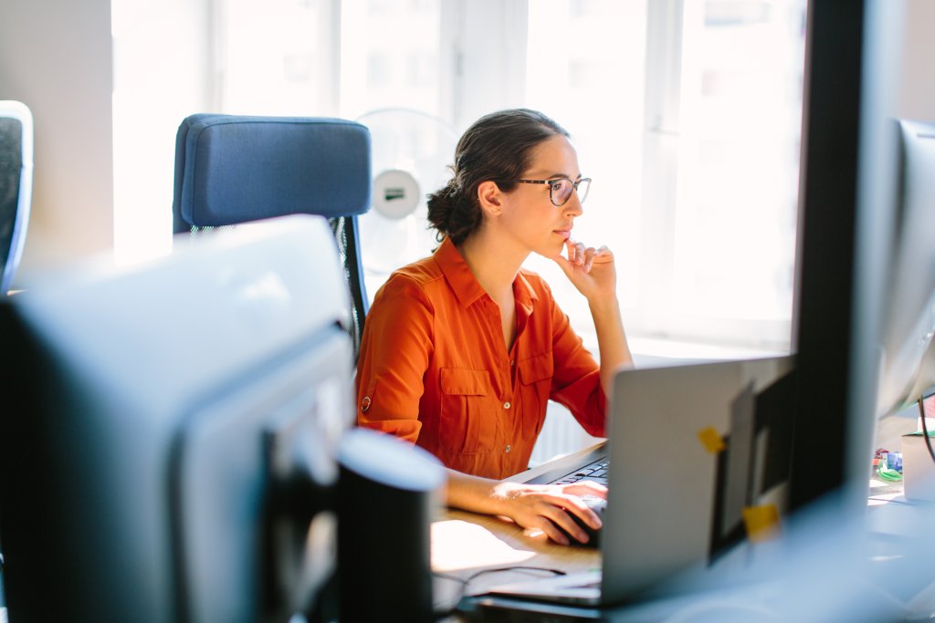 Frau arbeitet konzentriert an ihrem Laptop in einem modernen Büro.