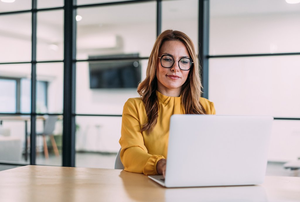 Elegante Geschäftsfrau sitzt in ihrem Büro und benutzt Laptop.