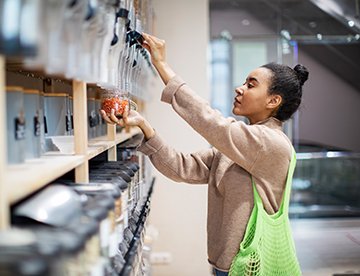 Frau packt Lebensmittel in einem modernen Geschäft mit nachhaltigen Produkten. aus dem Artikel So konsumiert die Generation Y