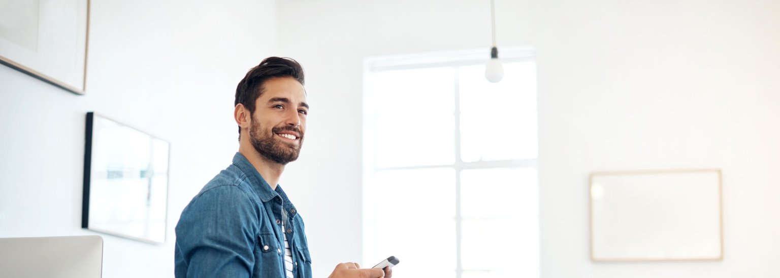 Ein junger Mann benutzt sein Handy in einem modernen, hellen Raum.