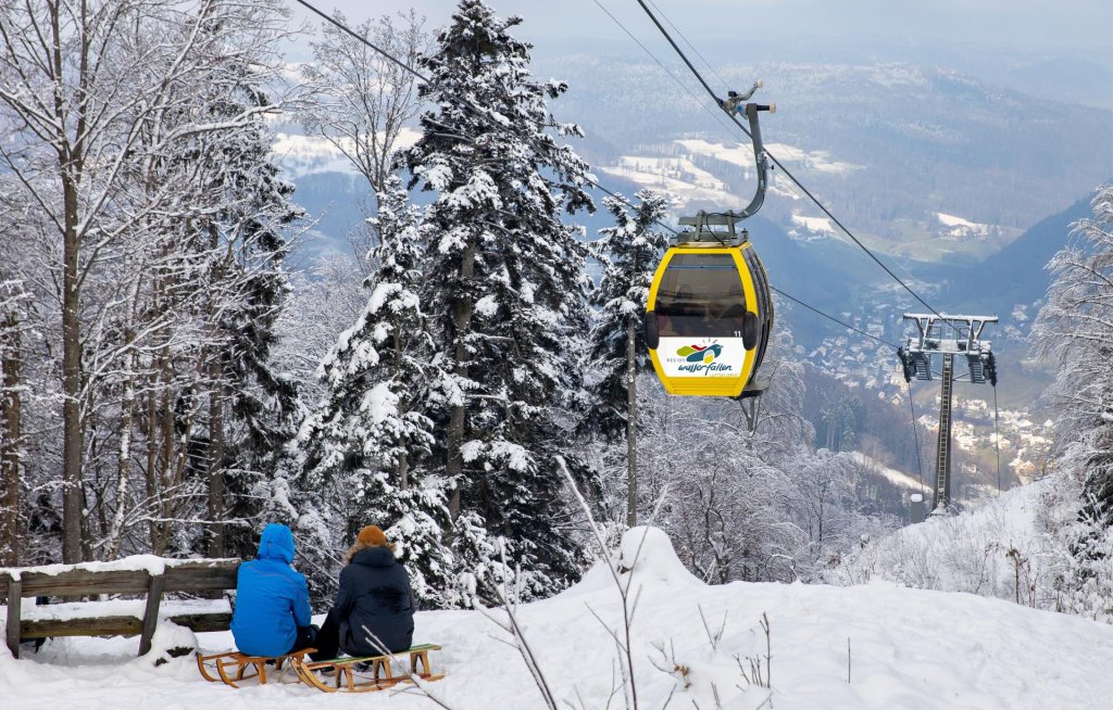 Zwei Personen sitzen im Schneeschnee und genießen die Winterlandschaft.