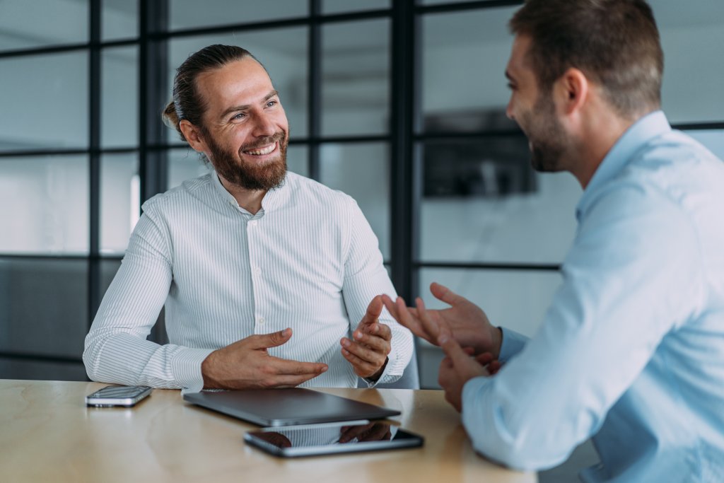 Zwei Männer im Gespräch, im modernen Büro mit BLKB Logo im Hintergrund