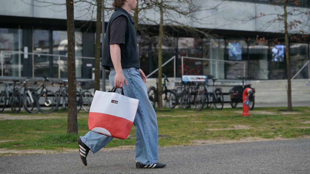 Ein junger Mann läuft mit einer Unikat-Tasche der BLKB.