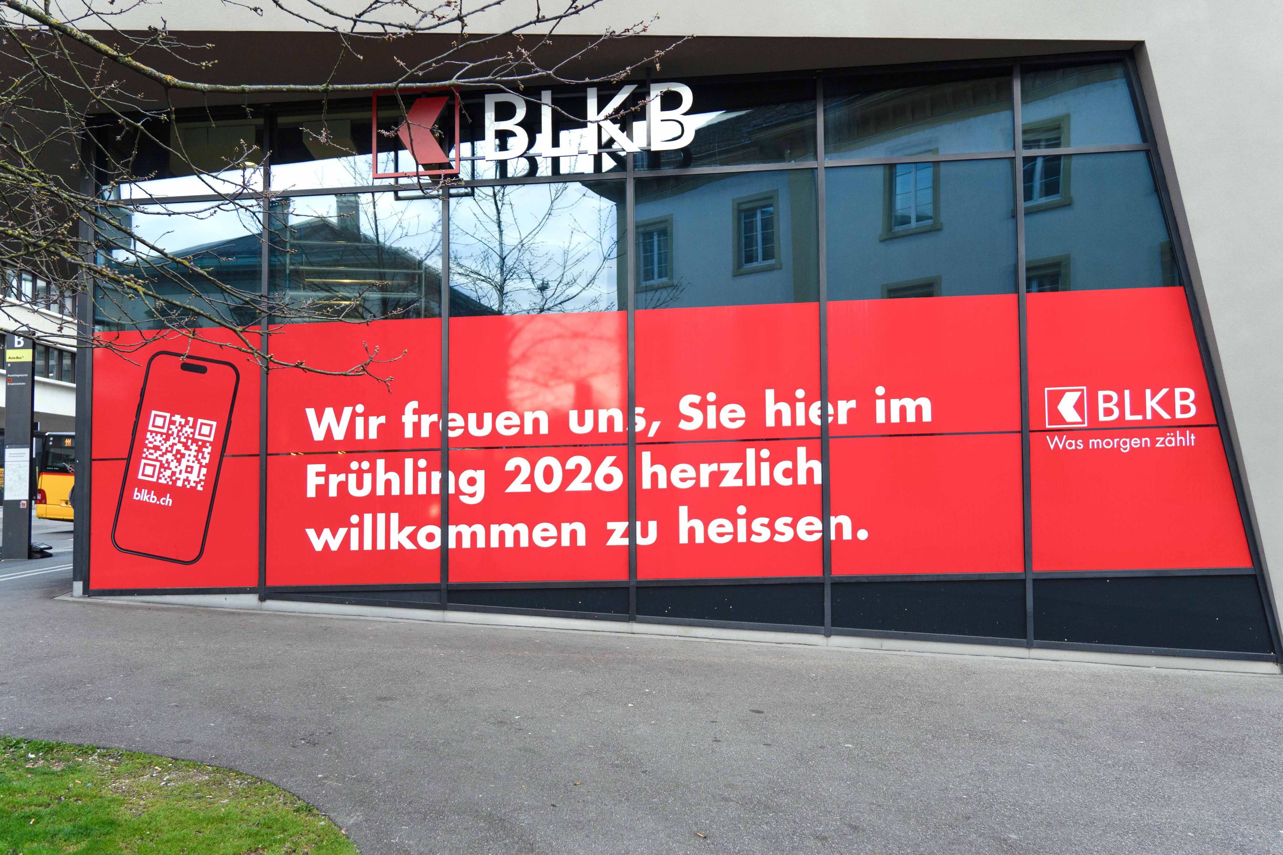 Fensterfront mit roten Werbebanner der BLKB-Niederlassung in Liestal und QR-Code zu blkb.ch.