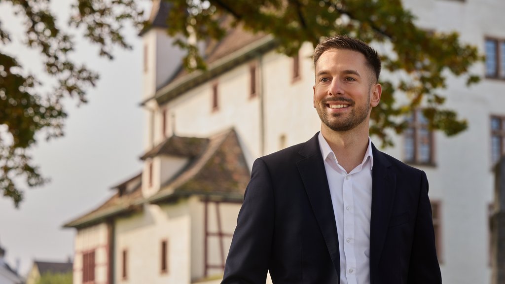 Pascal Inderwildi im Anzug vor einem historischen Turmgebäude in der Nordwestschweiz.